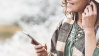Woman listening music with her mobile phone in first snow