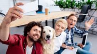 happy young people taking selfie with dog in office