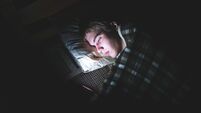 Depressed teenager on his phone in the dark.