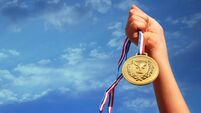 child hand raised, holding gold medal against sky. education, success, achievement, award and victory concept.