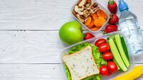 school lunch boxes with sandwich and fresh vegetables, bottle of water, nuts and fruits