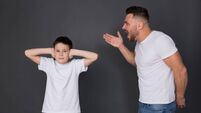 Nervous father screaming at son, boy closing ears