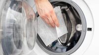 Hand dropping dryer aromatic sheets in a washing machine