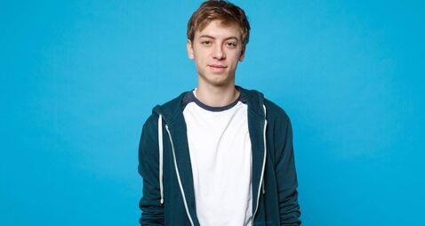 Portrait of attractive handsome young man in casual clothes standing isolated on blue wall background in studio. People sincere