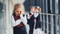 Little girl gets bullied. Conception of harassment. School kids in uniform together in corridor