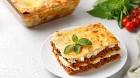 Portion of Homemade Italian lasagna. Delicious Lasagne with bolognese meat sauce and basil on white plate. Hot Tasty Lasagna wit