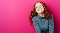 Young laughing woman against pink background