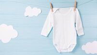 Baby clothes and white clouds on a clothesline, blue background