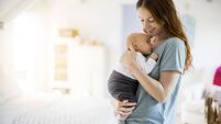 Happy beautiful woman carrying son in bedroom