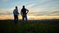 Shot of two farmers standing on a farm during sunset