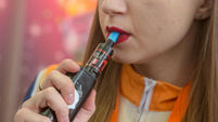 A young woman smokes electronic cigarettes