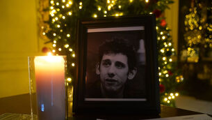 <p>A candle burns next to a photograph of The Pogues frontman Shane MacGowan at the Mansion House, in Dublin, after a book of condolence was open by the Lord Mayor of Dublin. Picture: Brian Lawless/PA Wire</p>
