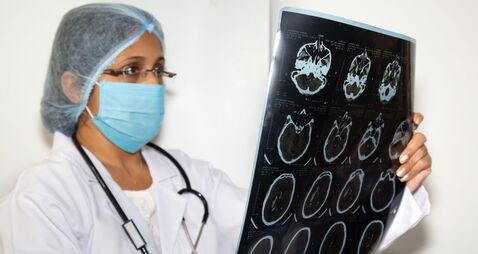 Indian female neurologist examine a brain CT scan plate at a healthcare clinic